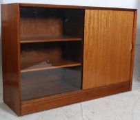 A retro Danish style teak library bookcase cabinet. Raised on plinth base with sliding glass door