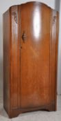 A 1930's Art Deco oak bachelors small wardrobe. The shaped door to centre having open storage within