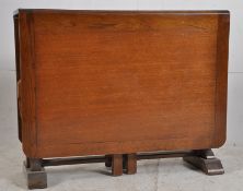 A 1930's Art Deco oak drop leaf gate leg dining table being raise on bulbous supports with deep