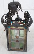 A stained glass and wrought metal hallway lantern. Coloured glass panels with rococo scrolls and