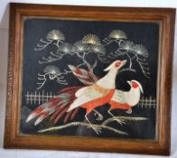 An early 20th century silk work picture of pheasants, being framed and glazed in an ornate carved