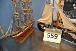 A vintage model of a clipper ship, with rigged sails, along with a model pond yacht. Both on
