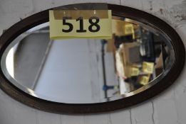 An antique inlaid oval wall mirror with inlaid detal to edge.