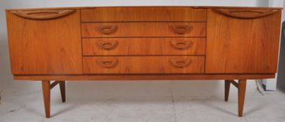 A 1970`s Danish teak sideboard. The tapered legs united by stretchers supporting a low and wide