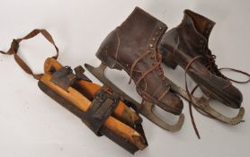 A pair of leather vintage ice skates together with a wooden pair of strap on ice skates