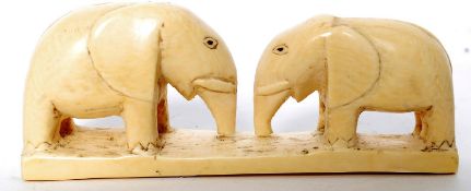 An antique carved bone statue of two elephants. Carved detail to eyes. 14cm long.