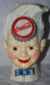 A vintage cast metal Coca Cola advertising money box, of a boy with whispy white hair, with Coca