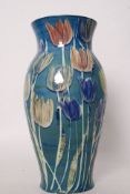 A large baluster vase with tulip decoration on blue / green ground, hand signed to base 38cm high