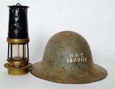 A WWII Bristol BAC firemans tin helmet along with a vintage 77 Miners Lamp with brass top and base.