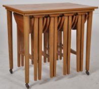 A retro 1970`s teak quartetto nest of tables. The large table supporting 4 drop leaf tables beneath