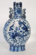 A Kangxi period blue and white moon flask bearing chasing dragons and leafy scrolls to centre with