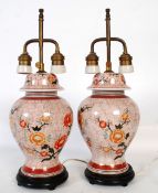 A pair of Chinese brass table lamps having famille rose baluster decorated bodies with brass heads