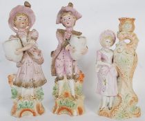 A pair of bisque figurines and one other.