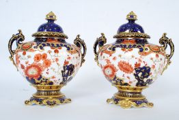 A pair of early 20th century Royal Crown Derby Imari style pattern urns. Being boldly decorated and