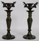 A pair of 19th century bronze candlesticks having stags heads to either side of the sconces, both