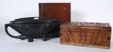 Two carved boxes depicting African scenes along with another shaped like a book