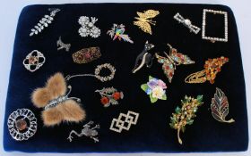 A collection of 20 costume jewellery brooches, on a display board including a fur butterfly, white