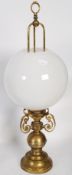A large brass coaching lamp wired for electricity having a bulbous white glass shade. Measures
