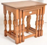 A 20th century gold oak nest of tables. Turned legs united by stretchers with graduating table