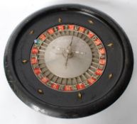 A 1920's wooden casino gaming roulette wheel with spinning cased metal numbered plate to ebonised