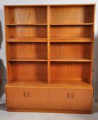 A 1970's G Plan teak wood double bookcase. The single base section having a series of cupboards.