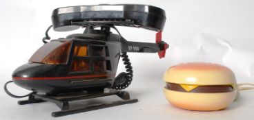 A vintage novelty telephone in the form of a helicopter along with another in the form of a