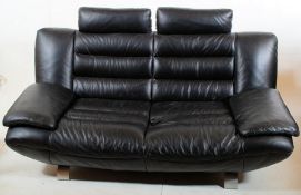 A modernist retro styled two seater black leather sofa settee raised on polished steel supports -