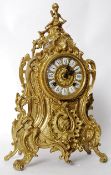 A German gilded clock of Rococo form with cherubs on top. Marked FHS.