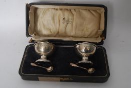 A cased pair of hallmarked silver blueglass lined salts.