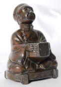 A bronze Chinese oriental figure of a man being seated holding a bowl.