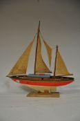 A 1940's model pond yacht having a wooden construction and canvase sails being raised on a later