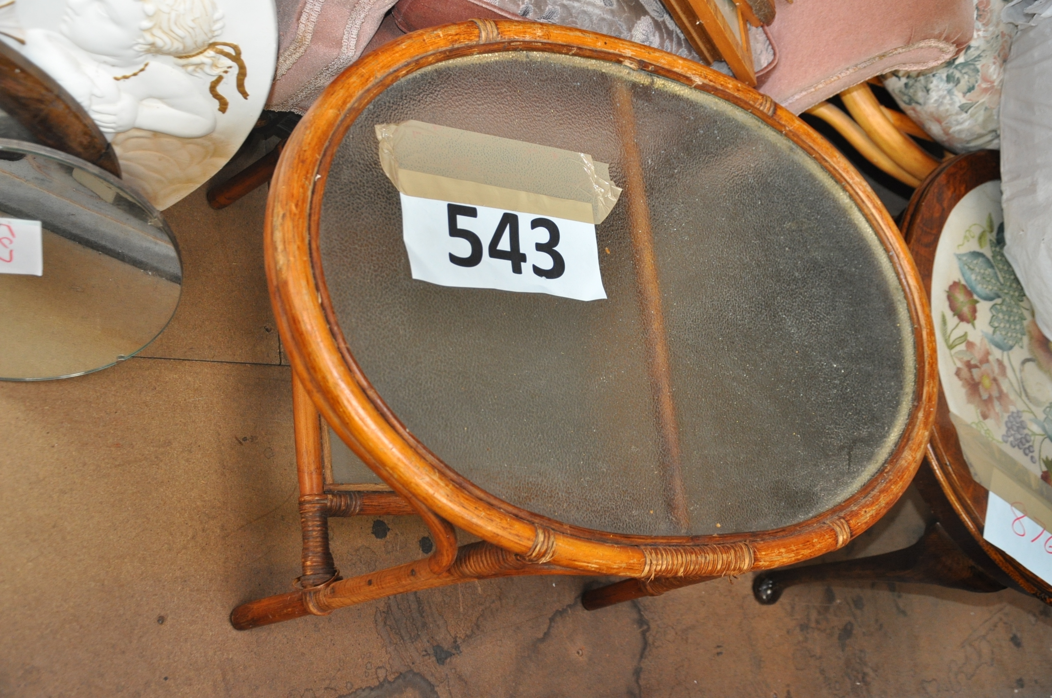 A glass topped conservatory wicker constructed table, oval shaped.