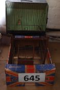 A vintage bird cage being wire framed together with a vintage wooden cased bird show cage with inset