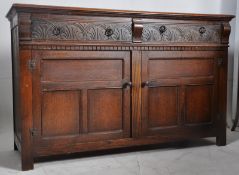 A Jacobean revival oak sideboard cabinet. Two short drawers over 2 cupboards having carved moulded