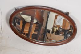 An oval mahogany mirror with inlaid decoration to edge