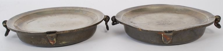 A pair of 19th century pewter plate warmers bearing illegible touch marks having armorial crests