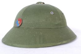 A 20th century Vietcong helmet with fabric outer lining complete with enamel badge to the front