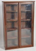 An early 20th century library bookcase cabinet having sliding glass doors with shelving set
