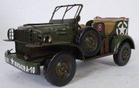 A pressed tin plate model of a military army jeep with moving wheels.