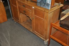 An early 20th century pine country dresser base. Raised on turned legs with dog kennel centre having