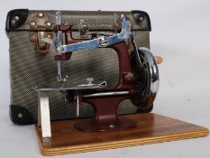 A 1950's original childs sewing machine mounted to a walnut plinth base complete with the original