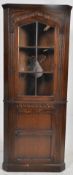 A Jacobean style oak corner cabinet in the manner of Jaycee / Old Charm. Leaded glass panels with