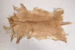 An African deer skin rug of tan colours. W 105 cm.