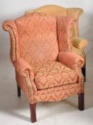 A pair of Georgian revival wing back armchairs bearing compliant fire labels. one in red, the