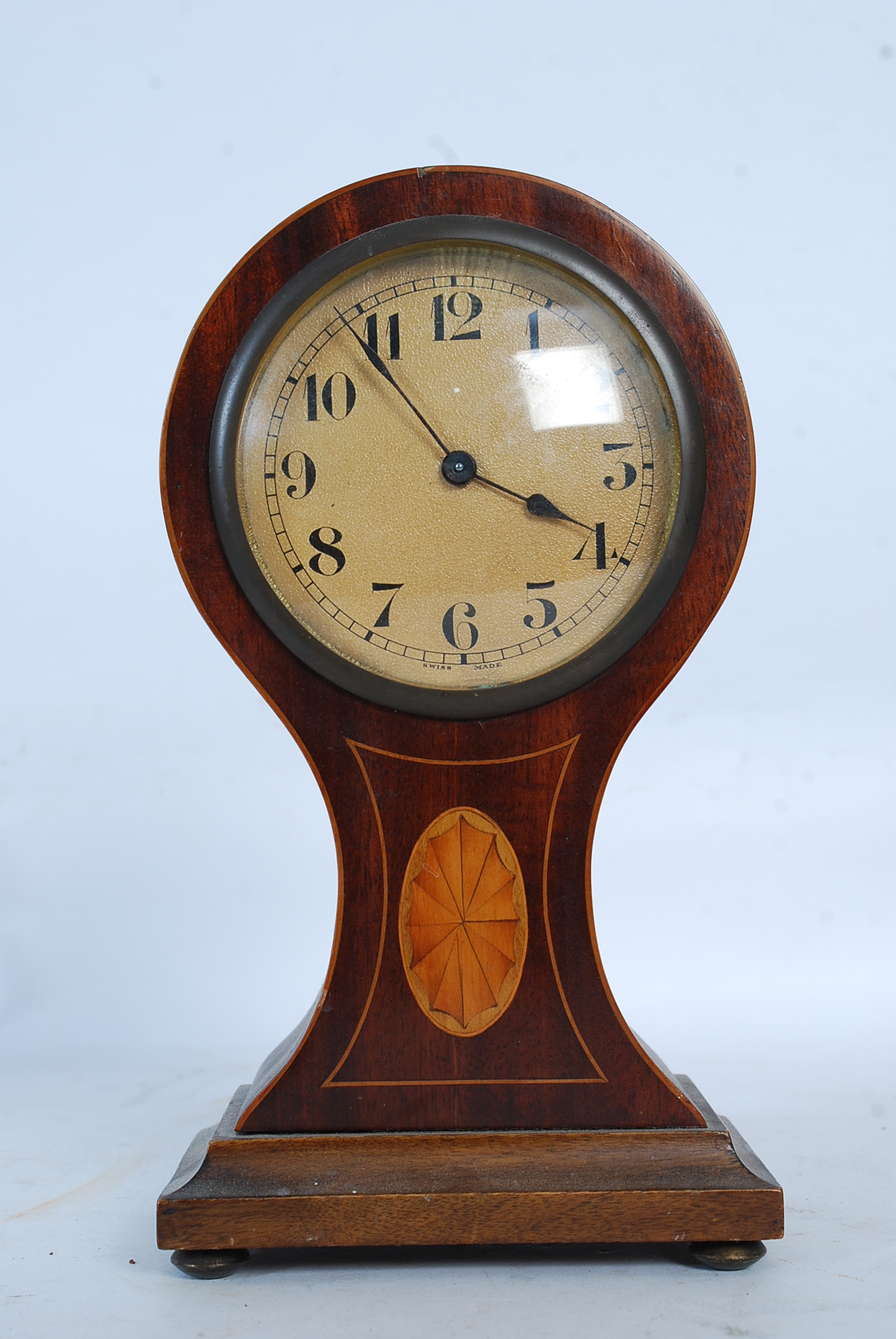 An Edwardian mahogany inlaid balloon clock having decorative enamel face with a Swiss brass movement