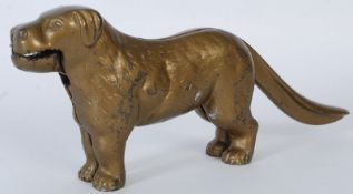 A vintage cast metal nut cracker in the form of a dog. Handle in the form of the tail and the