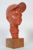 A bust of a young boy with hat mounted on a wooden plinth. Signed Paul Serste