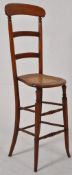 A late Victorian 19th century solid walnut childs posture chair. Turned legs united by stretchers
