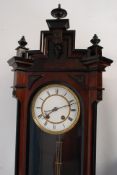 A Victorian Vienna style wall hanging clock with brass movement and enamel face, with pendulum.