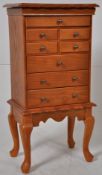 A large jewellery cabinet in the form of a chest on stand. Multiple drawers with hinged top
